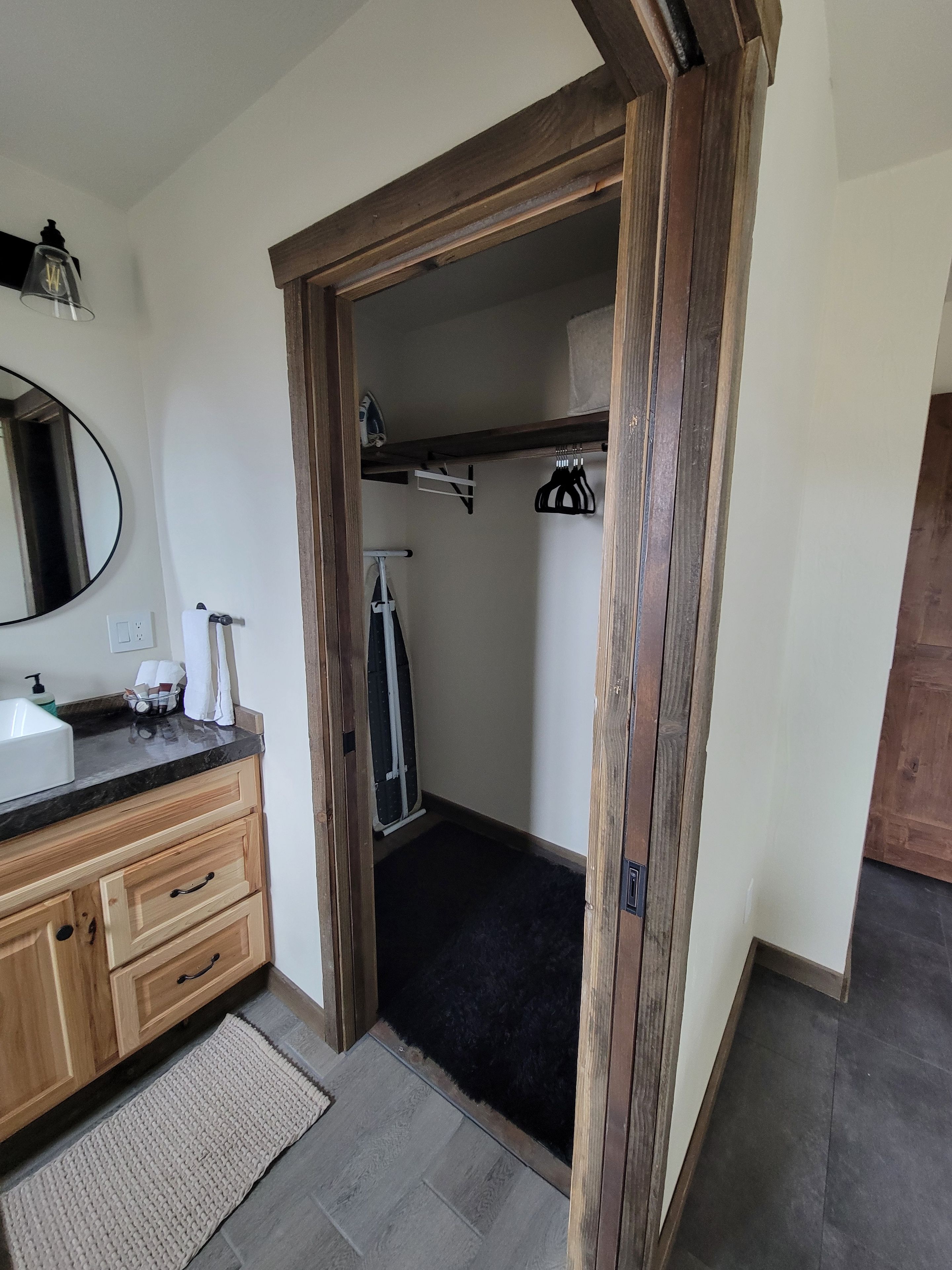 A bathroom with a wooden door, a sink with a mirror, and a towel rack.