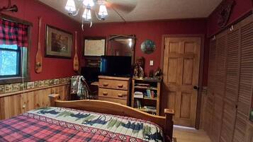 A bedroom with a bed, wooden dresser, and a television.