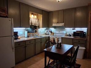A kitchen with a refrigerator, stove, microwave, and a dining table with chairs.