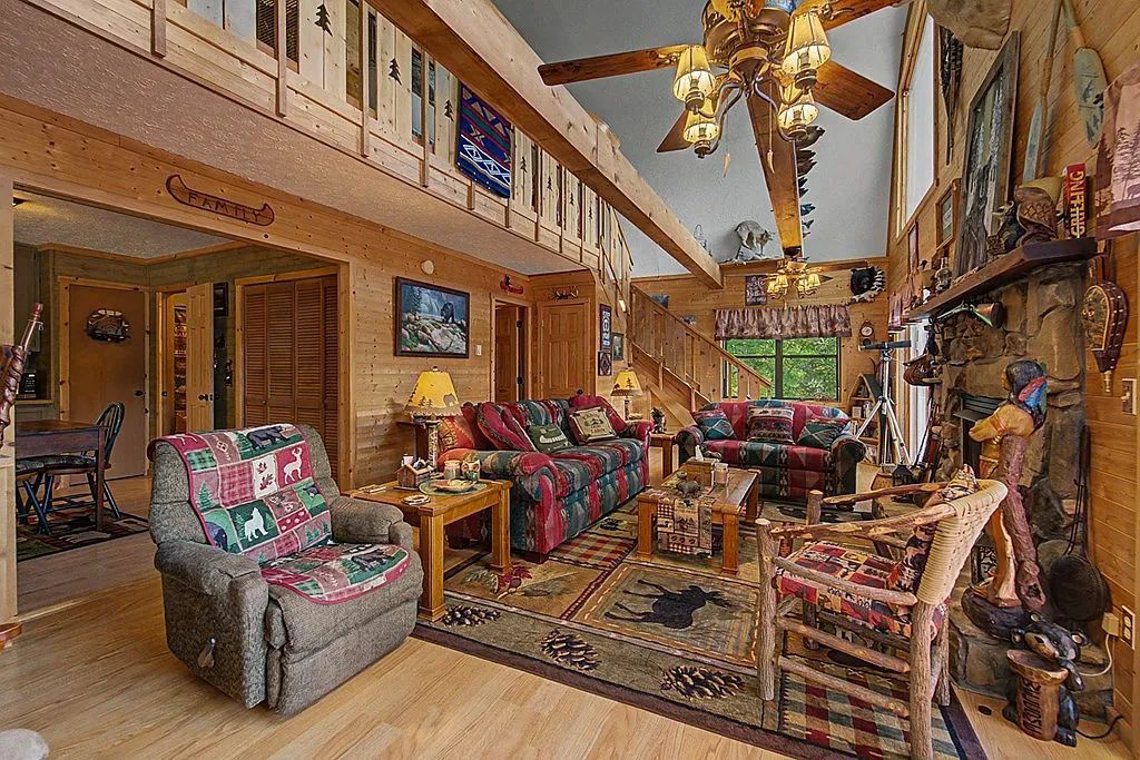 A spacious living room with a high ceiling, wooden beams, a large sofa set, a fireplace, and a collection of decorative items.