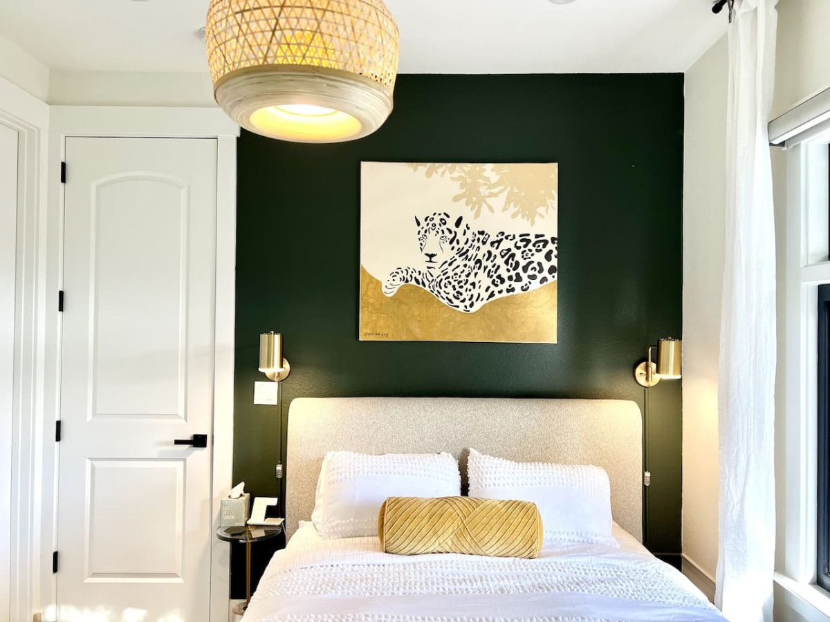 A bedroom with a bed, a wall-mounted artwork of a leopard, bedside lamps, and a door.