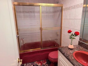 A bathroom with a glass-enclosed shower, a red toilet, and a sink with a vase of red roses. - Richmond Elegant Home-Luxury Stay close to YVR and center (Richmond)