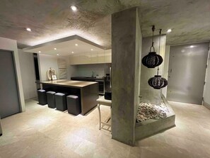 A modern kitchen with a central island, built-in seating, and a decorative rock feature. - Gorgeous Condado 3-Bedroom + 2 Bath w/ OceanView! (San Juan)