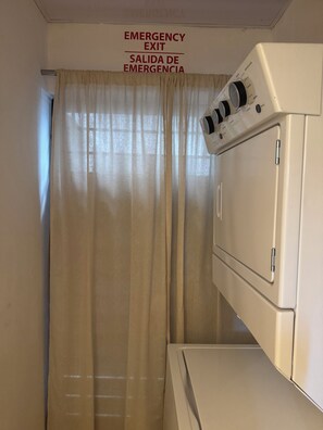 A laundry room with a washing machine and a sign indicating an emergency exit. - Spacious 3-bedroom apartment in peaceful Santiago de los Caballeros with AC (Santiago de los Caballeros)