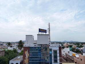 A hotel building with a signboard, surrounded by other buildings and a clear sky. - MIMO Hotels (Walajapet)