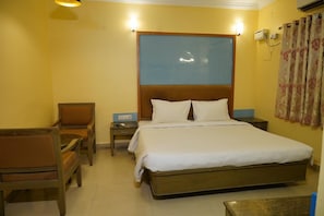 A hotel room with a bed, a chair, a nightstand, and a wall-mounted air conditioning unit. - MIMO Hotels (Vellore)