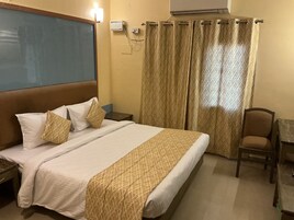 Habitación de hotel con cama, una silla, un escritorio y aire acondicionado de pared.