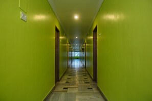 A hallway with green walls and a patterned floor, leading to a bright room at the end. - MIMO Hotels (Walajapet)