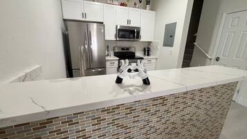 A kitchen with white cabinets, stainless steel appliances, and a white countertop.