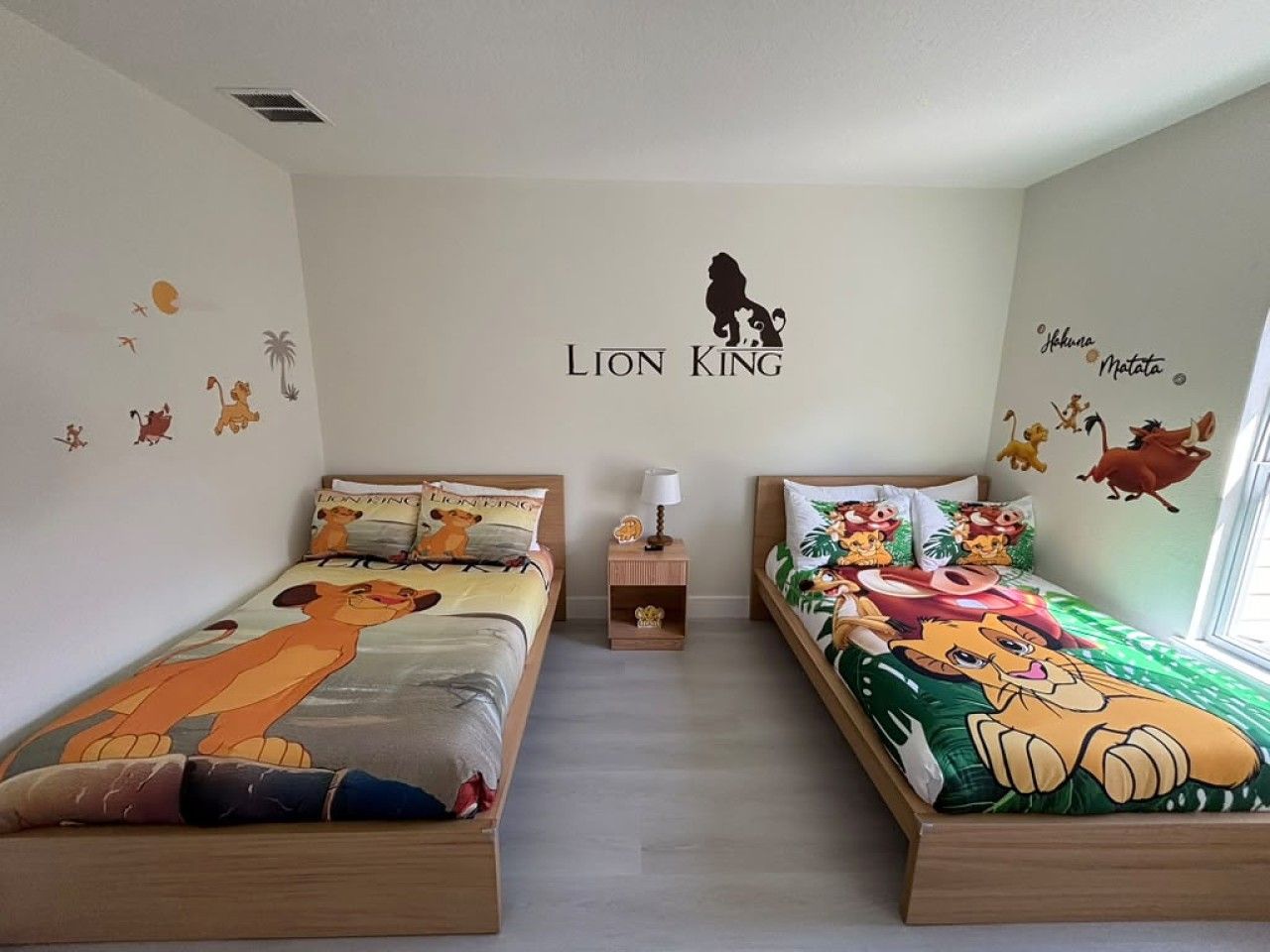 Een slaapkamer met twee bedden, elk versierd met een beddeken met het thema De Koning Leeuw.
