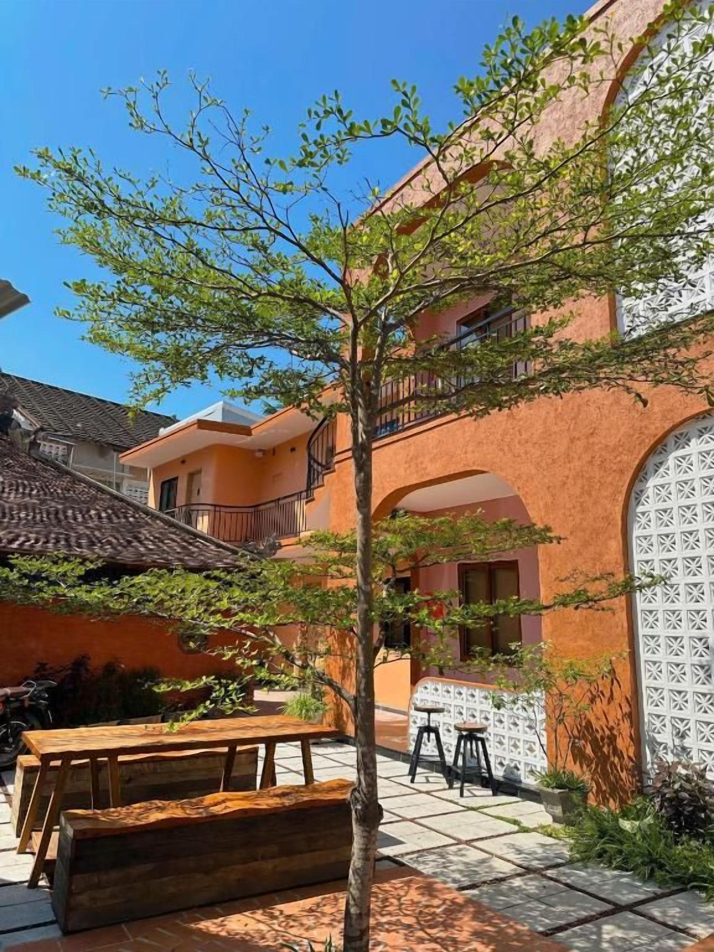 Un patio con un banco de madera, una mesa y un árbol.