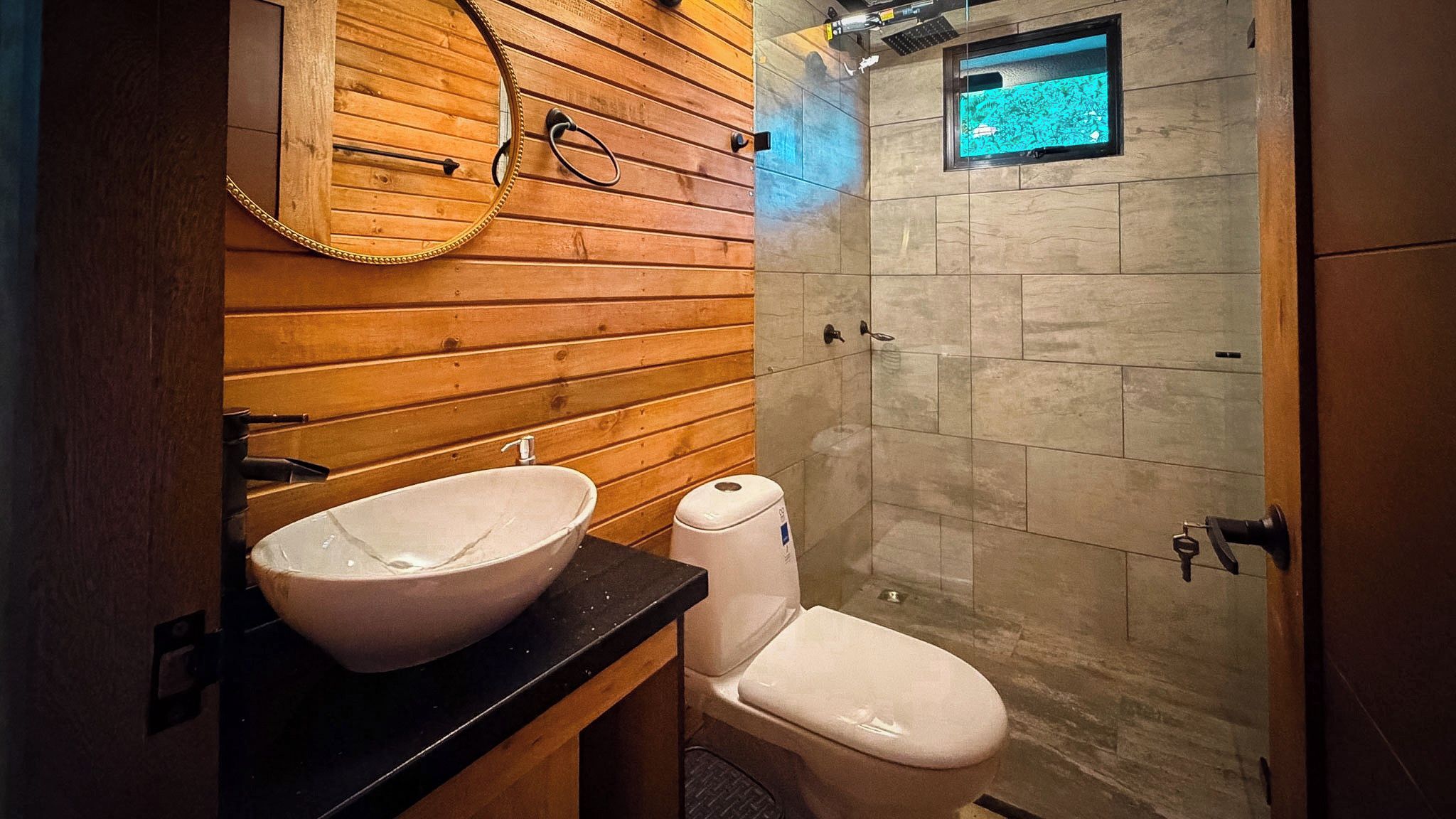 A bathroom with a wooden vanity, a white sink, and a shower with a glass door.
