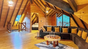 Quarto de sótão aconchegante com teto de madeira, um sofá e uma mesa de centro redonda.