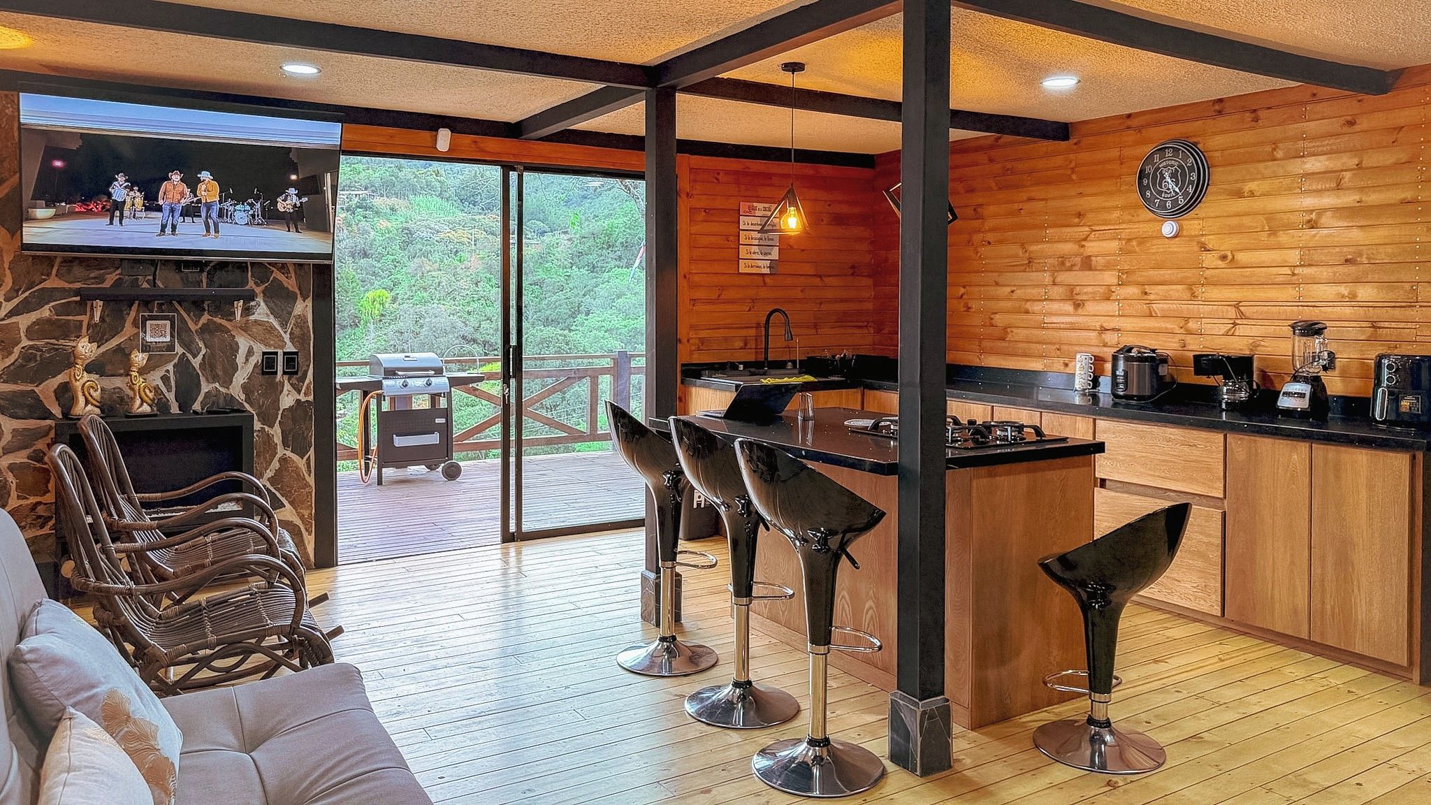 A modern kitchen with a stone fireplace, wooden accents, and a bar area with stools.