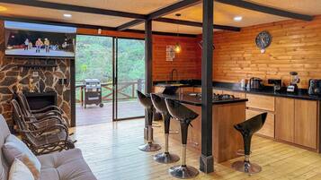 A modern kitchen with a stone fireplace, wooden accents, and a bar area with stools.