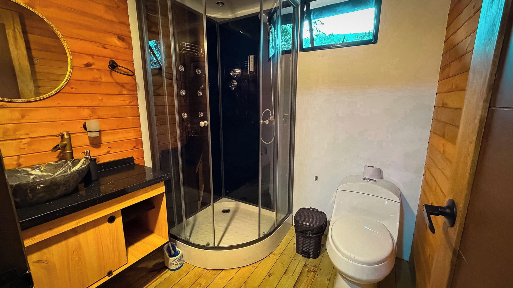 Ett badrum med en dusch som är avskärmad med glasväggar, ett handfat med en bänkskiva i marmor och en toalett.