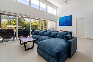 A modern living room with a sectional sofa, a coffee table, and a large window providing a view of the outdoors. - Serene, Contemporary Retreat with Plunge Pool (Playa Avellanas)