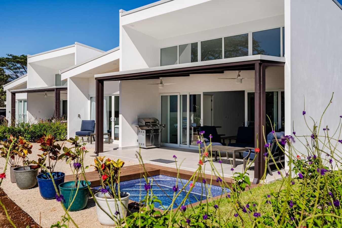 Ein modernes Haus mit Schwimmbad, Sitzgelegenheiten im Freien und Grillplatz.