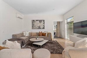 Ein modernes Wohnzimmer mit einer Eckcouch, einem runden Couchtisch und einem Flachbildfernseher.