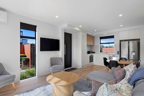 A modern apartment with a living room, dining area, and kitchen. - Modern Merivale Gem | Flexible Beds & Parking (Christchurch)