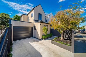 Ein modernes, zweistöckiges Haus mit Garage, Auffahrt und einem angelegten Garten mit Baum.