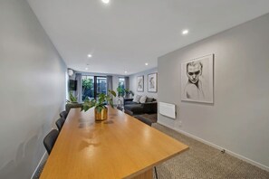 A modern interior with a wooden conference table, seating, and artwork on the walls. - Modern CBD retreat with parking and courtyard (Christchurch)