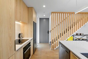 A modern kitchen with wooden cabinets, a built-in oven, and a stainless steel dishwasher. - Modern Town House in the Heart of Merivale (Christchurch)