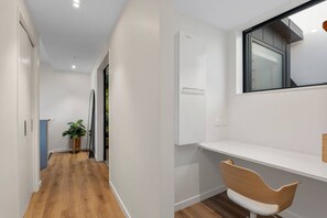 Ein Flur mit Holzboden, einer Topfpflanze und einer weißen Wand mit Fenster.
