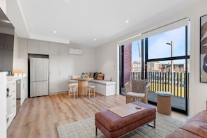 Eine moderne Wohnung mit Küche, Essbereich und einem Balkon mit Blick auf die Stadt.