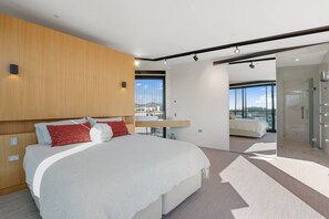 Ein modernes Hotelzimmer mit einem großen Bett, einer Glasdusche und Blick auf die Stadt.