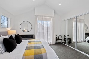 Ein Hotelzimmer mit Bett, Schreibtisch, Stuhl, Spiegel und einer Schiebetür.