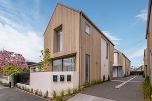 Ein modernes Wohngebäude mit zwei Etagen, geneigtem Dach, großen Fenstern und minimalistischem Design.