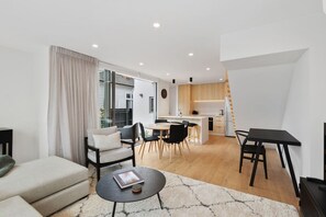 Ein modernes Wohnzimmer mit einer Couch, einem Couchtisch und einem Essbereich mit Stühlen und einem Tisch.