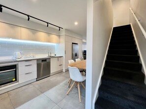 Eine moderne Küche mit Essbereich, einer Treppe und Blick zum Wohnbereich.