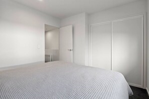 Ein Schlafzimmer mit einem großen Bett, einem Kleiderschrank und einer Tür zu einem Badezimmer.