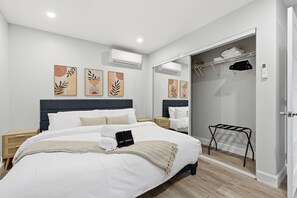 Ein modernes Schlafzimmer mit einem großen Bett, einem begehbaren Kleiderschrank und Kunstwerken an den Wänden.