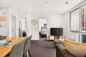 Une chambre d’hôtel moderne dotée d’un coin repas, d’une télévision et offrant une vue sur la ville.