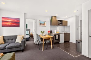 Une chambre d’hôtel moderne dotée d’un coin repas, d’une kitchenette et offrant une vue sur la ville.