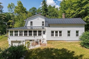 A two-story house with a garage, a covered porch, and a chimney. - Lake Sunapee Swim & Ski Retreat (Newbury)