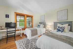 Une chambre avec deux lits, un bureau avec une télévision, un télescope et une fenêtre donnant sur un paysage verdoyant.