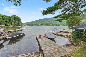 A dock with boats and chairs, surrounded by trees and hills. - Lake Sunapee Swim & Ski Retreat (Newbury)