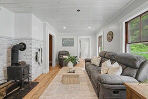 Una sala de estar moderna con chimenea, sofá de cuero y un letrero que indica la ubicación de la casa.