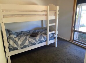 A bunk bed with a ladder, a patterned bedspread, and a window with a view of greenery. - Wendale Shores on Cave St - minutes to the beach (Goolwa Beach)