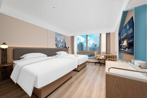 A hotel room with a large bed, a desk, a chair, and a view of the city.