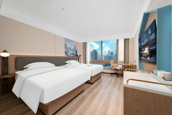 A hotel room with a large bed, a desk, a chair, and a view of the city.