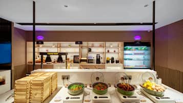 Een buffetruimte met diverse food stations, waaronder een gekoeld gedeelte en een toonbank met etenswaren.