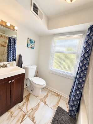 A bathroom with a toilet, sink, and shower curtain. - Chic 3-bedroom apartment with AC in Atlantic City (Atlantic City)