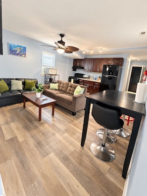 A modern living room with a sofa, coffee table, and a dining area with a table and chairs. - Chic 3-bedroom apartment with AC in Atlantic City (Atlantic City)