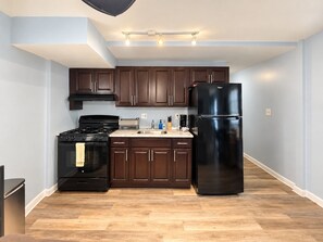 A modern kitchen with dark wooden cabinets, a black stove, and a black refrigerator. - Chic 3-bedroom apartment with AC in Atlantic City (Atlantic City)