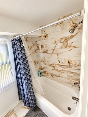 A bathroom with a bathtub, shower, and a window with blinds. - Chic 3-bedroom apartment with AC in Atlantic City (Atlantic City)